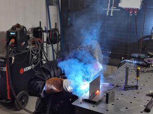 Laser-Aitan hitsaaja työssään työpöydän ääressä